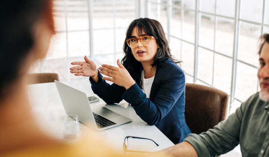 Professional woman talking to her team in an office meeting. Young business woman having a discussion with her colleagues. Group of business professionals brainstorming in an office.