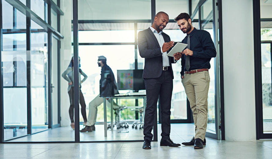 two coworkers looking at a tablet